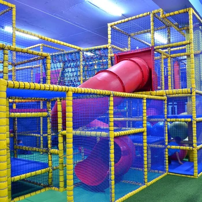 Multi-level soft play climbing frame with red tube slides at Oasis Fun indoor play centre, Bournemouth