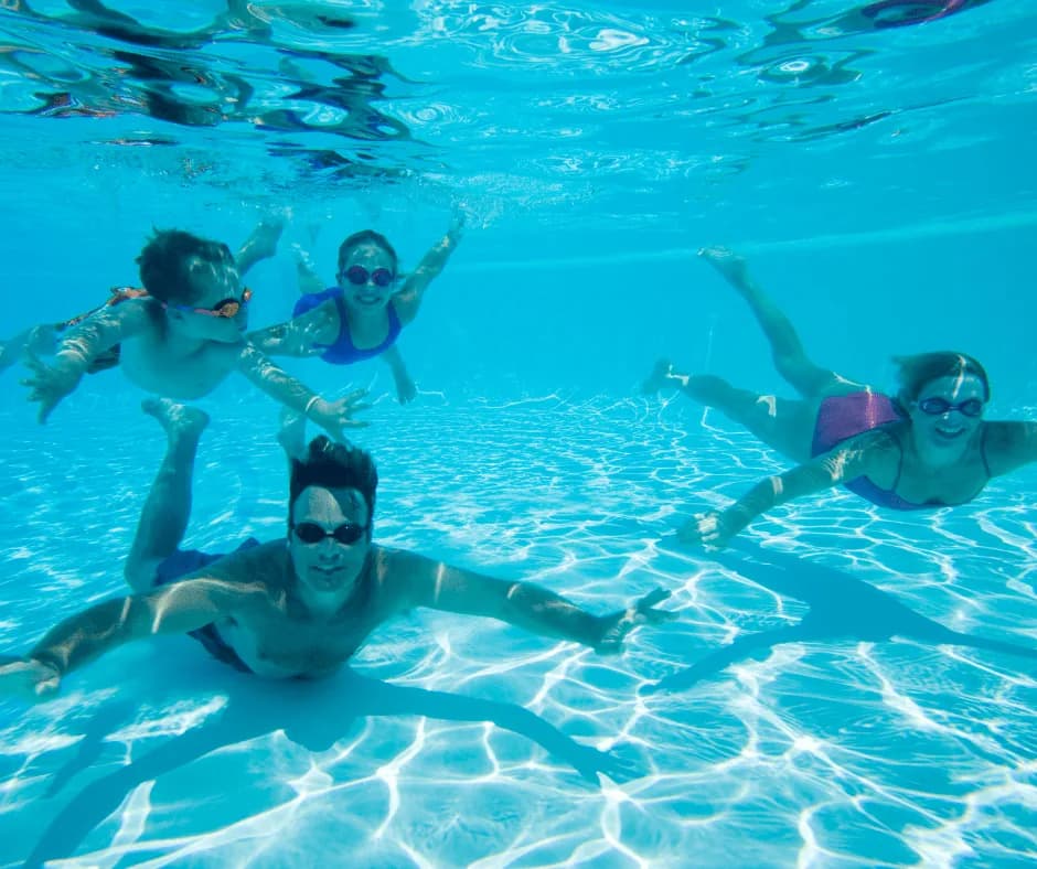 Family swimming at Harvey Hadden Sports Village swimming pool with two adults and two children underwater