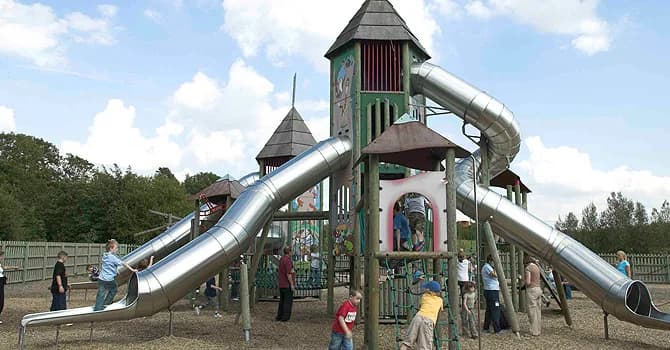 Outdoor play area at Conkers with multi-level wooden play structure and slides