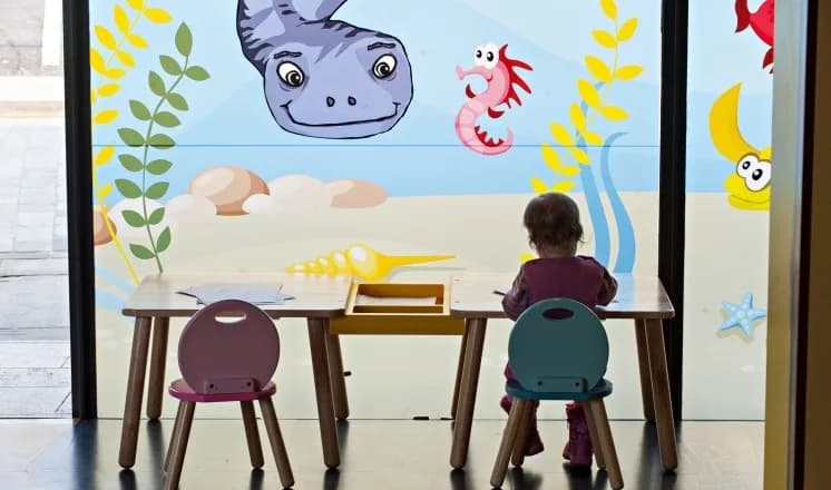 Play area at Lincoln Museum with a colourful underwater window mural and children's craft table