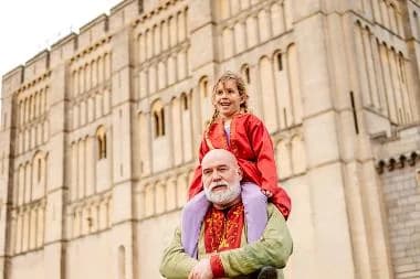Child on a man's shoulders in front of Norwich Castle keep