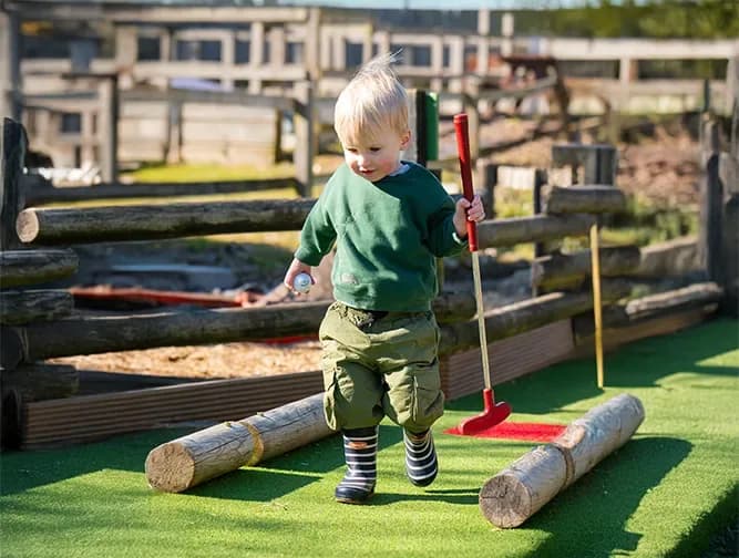Child playing mini-golf at Woodside Animal Farm
