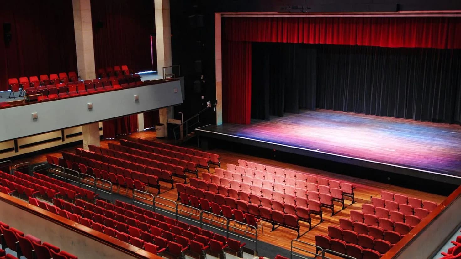 The auditorium of Alban Arena, St Albans, with rows of red seats facing the stage.