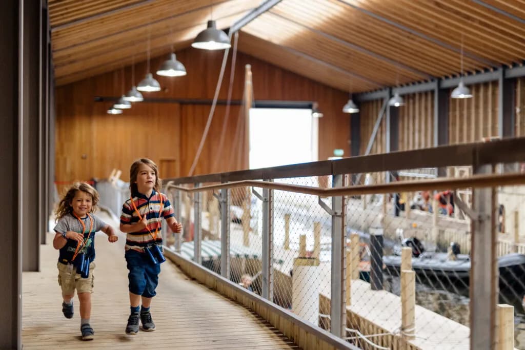 Two children running towards the photographer inside the Boathouse and Wet Dock at Windermere Jetty Museum