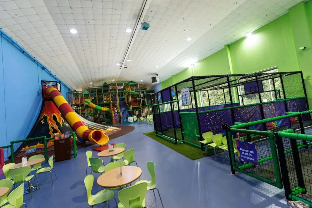 Indoor soft play centre with multi-level play structure, slides, sports cage and seating area
