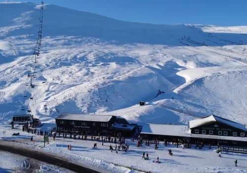 Glenshee Ski Centre main building, chairlift and slopes on a sunny winter day