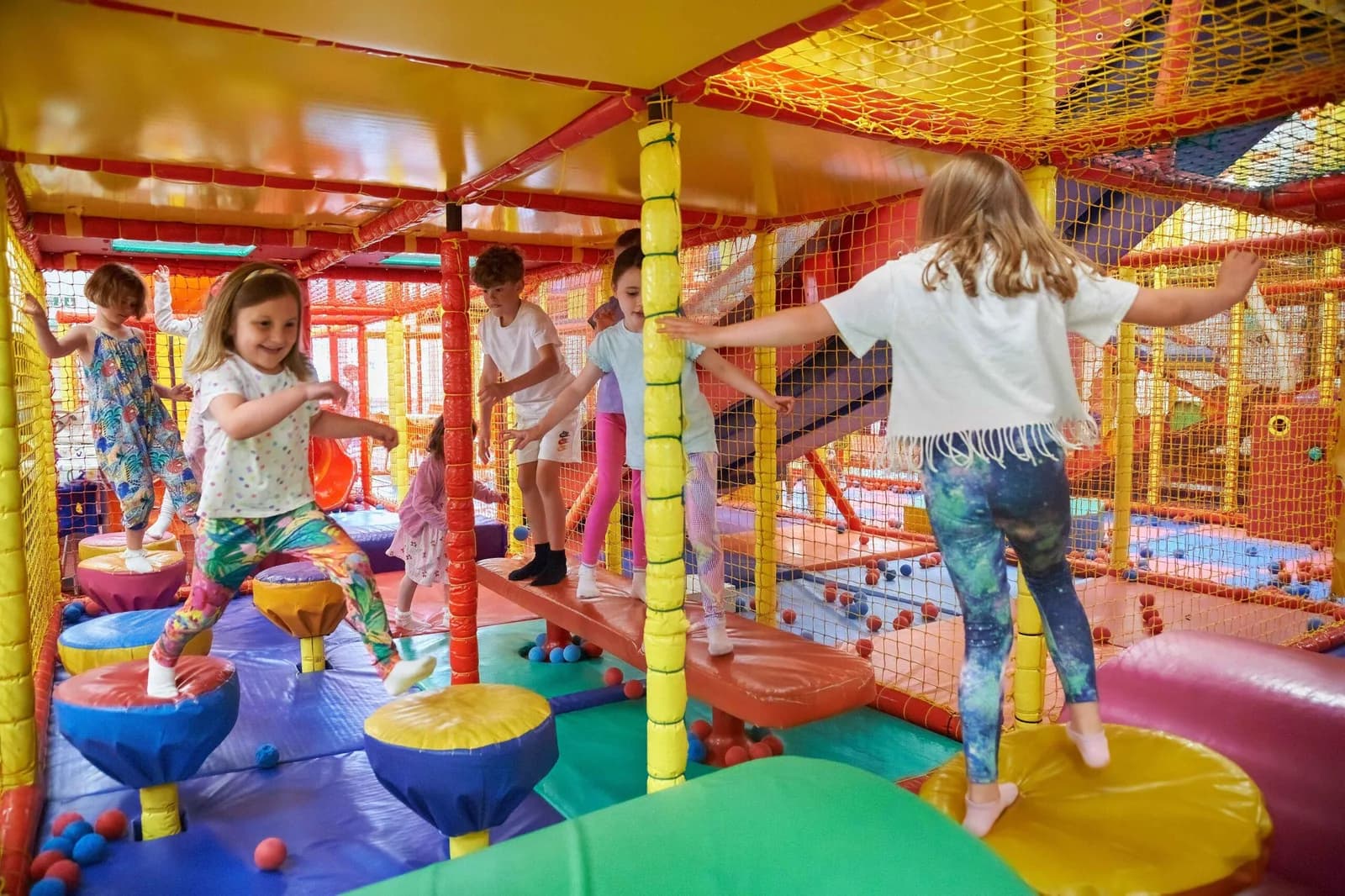 Children playing on colourful padded soft play equipment in the multi-level indoor play area at Amazon Adventure