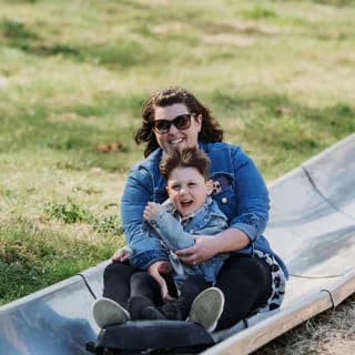 Woman and child sliding down the wide metal slide at Robin Hill Countryside Adventure