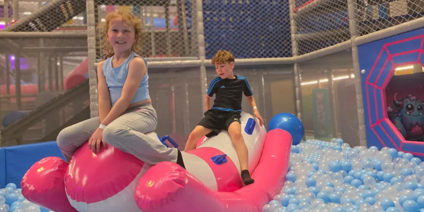 Children playing on a pink and white inflatable in the ball pit at FunParx Cardiff