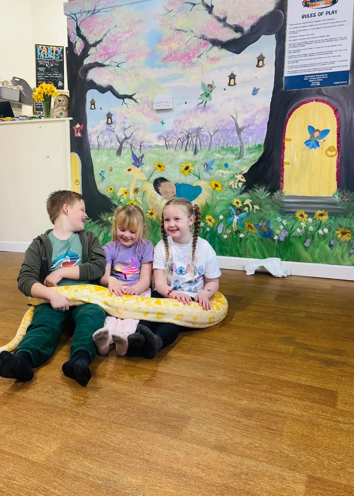 Children with a snake during an animal encounter session in the party area at Enchanted Adventures, Bridgend