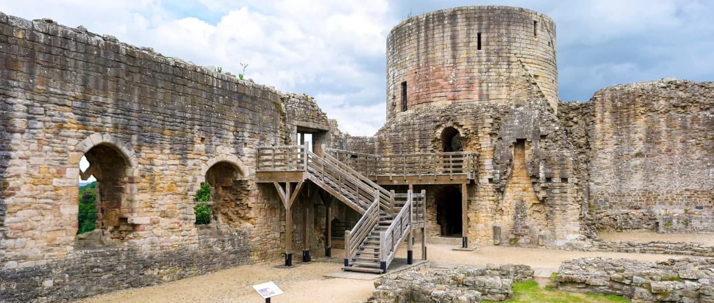 A view of the stone wall ruins of Barnard Castle with a wooden bridge