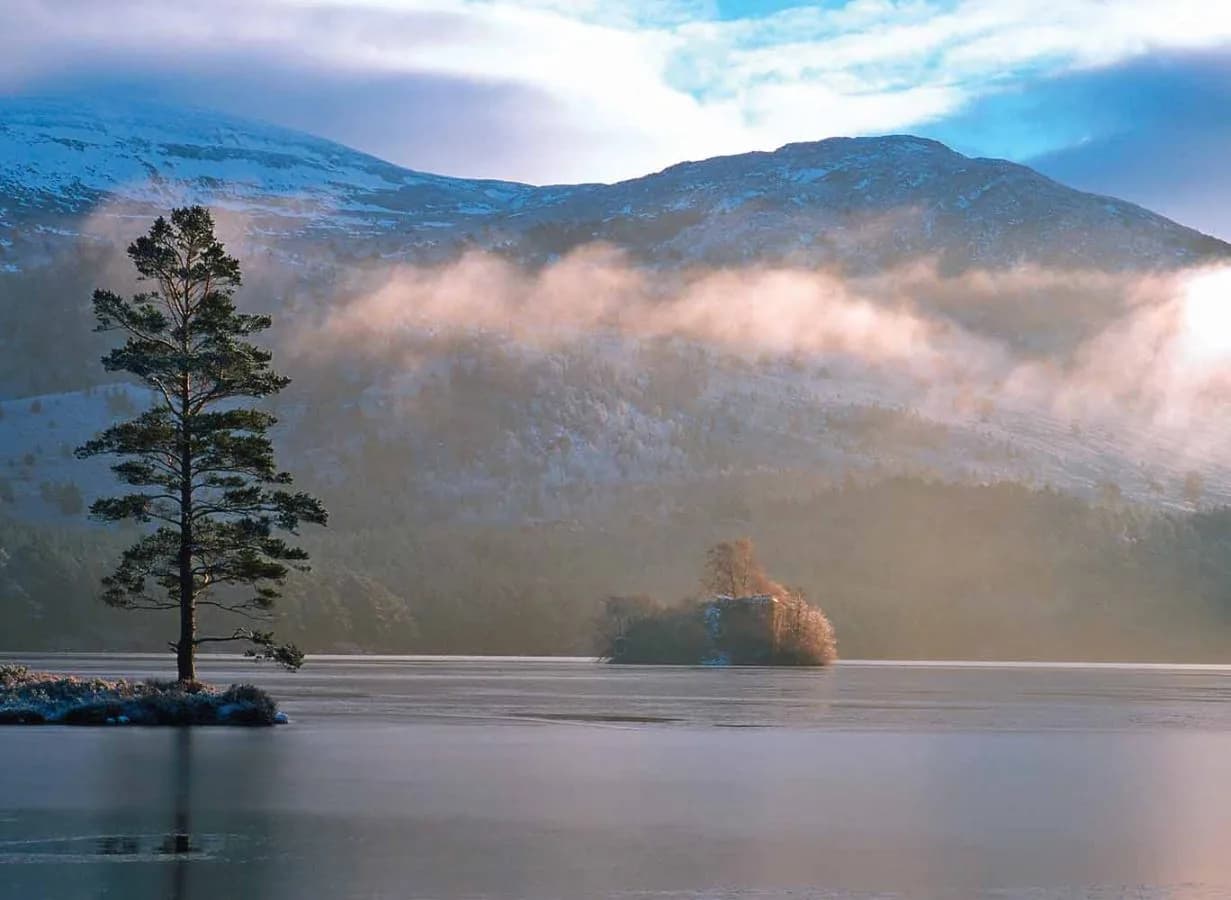 Loch an Eilein with castle ruins and Cairngorm mountains at Rothiemurchus Estate