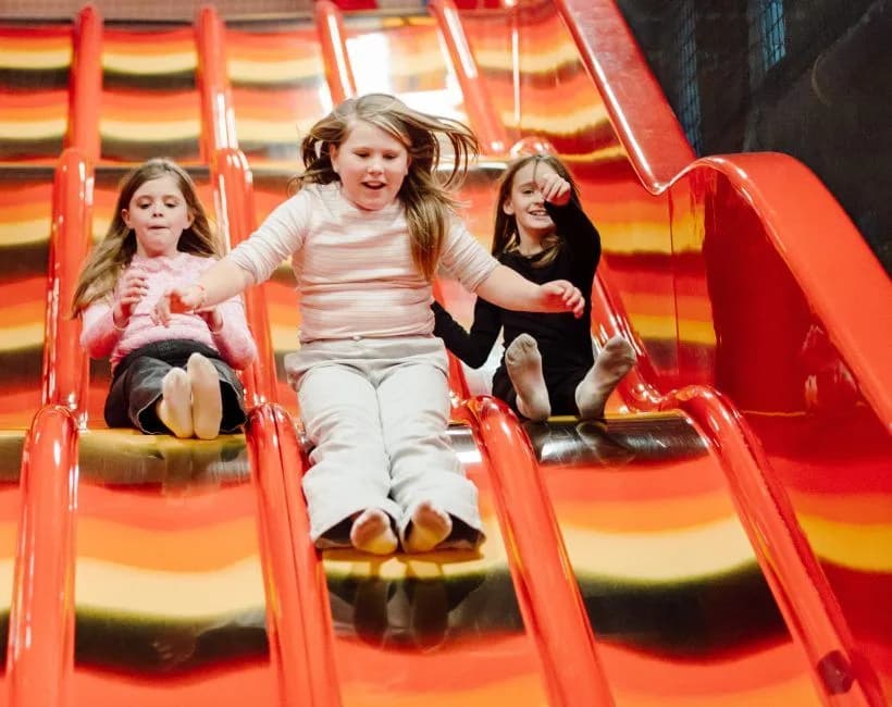 Children sliding down the multi-lane slide at Alley Cats Indoor Play Centre, The Jet Centre Coleraine