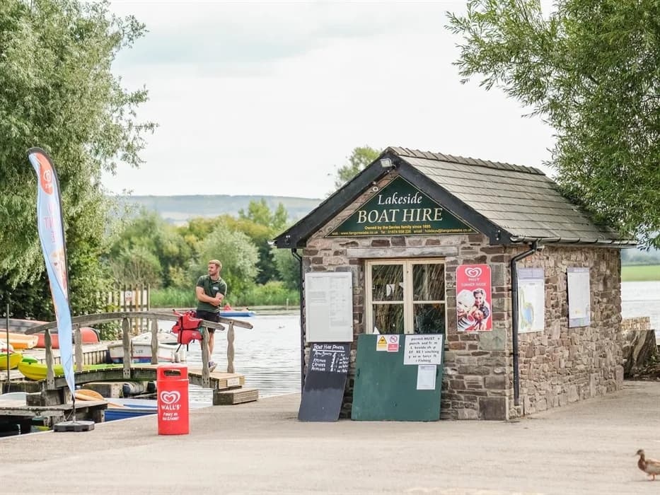 Lakeside boat hire building and kayaks moored at the jetty, Llangorse Lake
