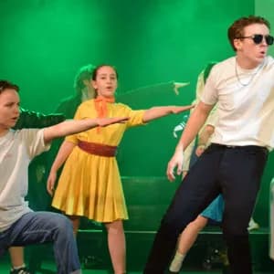 Young performers in a theatrical production under green stage lighting at The Brunton