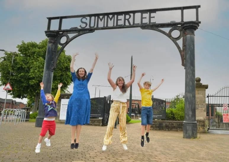 Family jumping for joy in front of the Summerlee Museum entrance archway