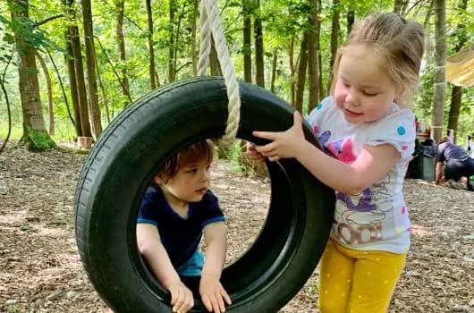 Child playing on a swing in the woods at Little Squirrels Forest School, High Ashurst