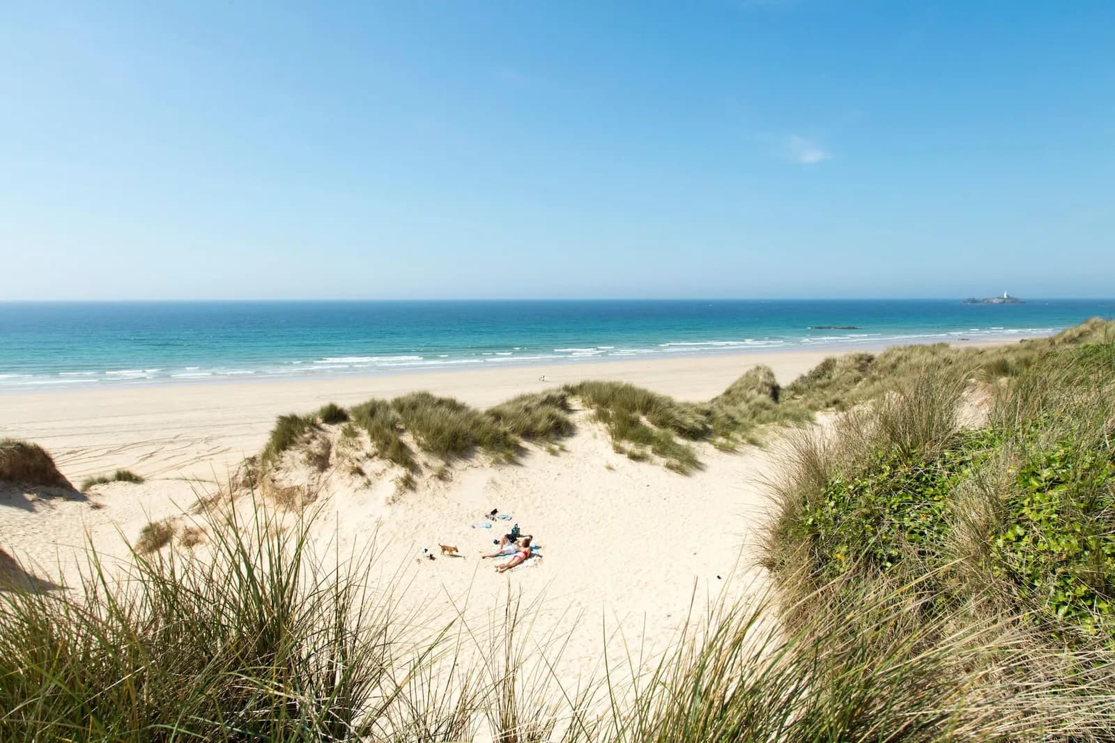 Golden sands and dunes of Hayle Towans Beach with Godrevy Lighthouse across St Ives Bay