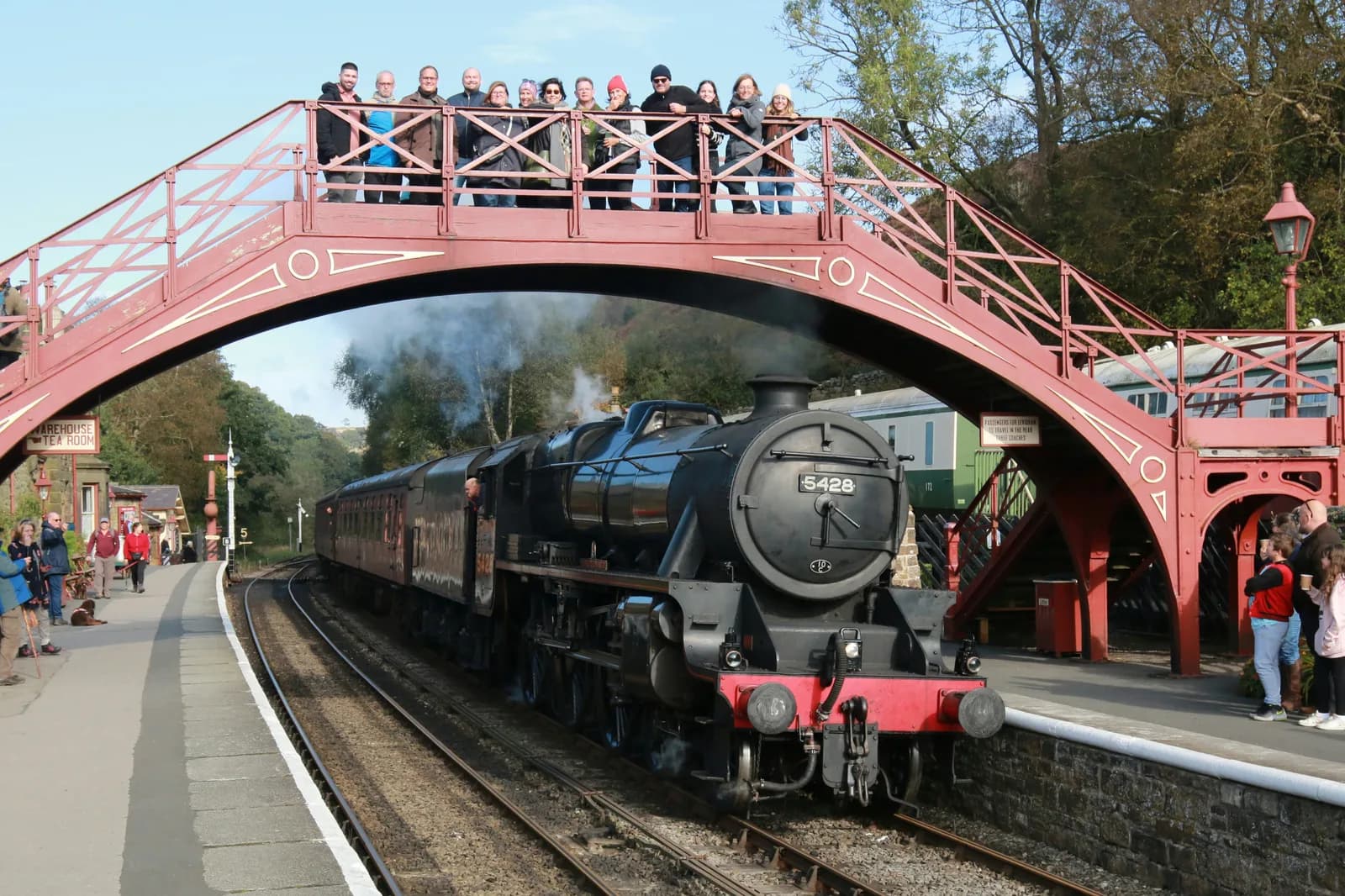 Visitors on the footbridge at Goathland Station as a heritage steam locomotive arrives on the North Yorkshire Moors Railway