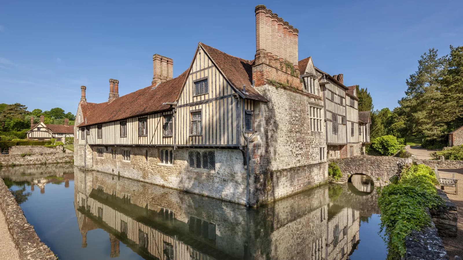 The south east corner of the medieval moated manor house Ightham Mote reflected on the moat