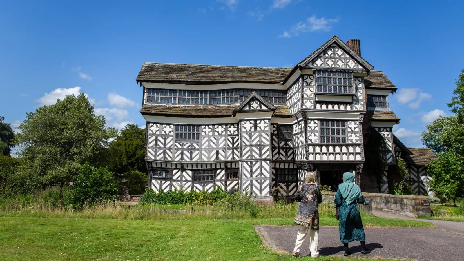 Two visitors walk towards the front of Little Moreton Hall, Cheshire