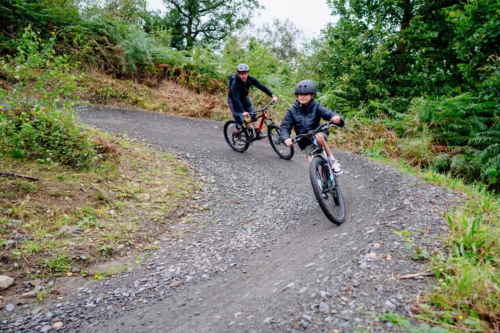 Adult and child mountain biking on a forest trail at Afan Forest Park