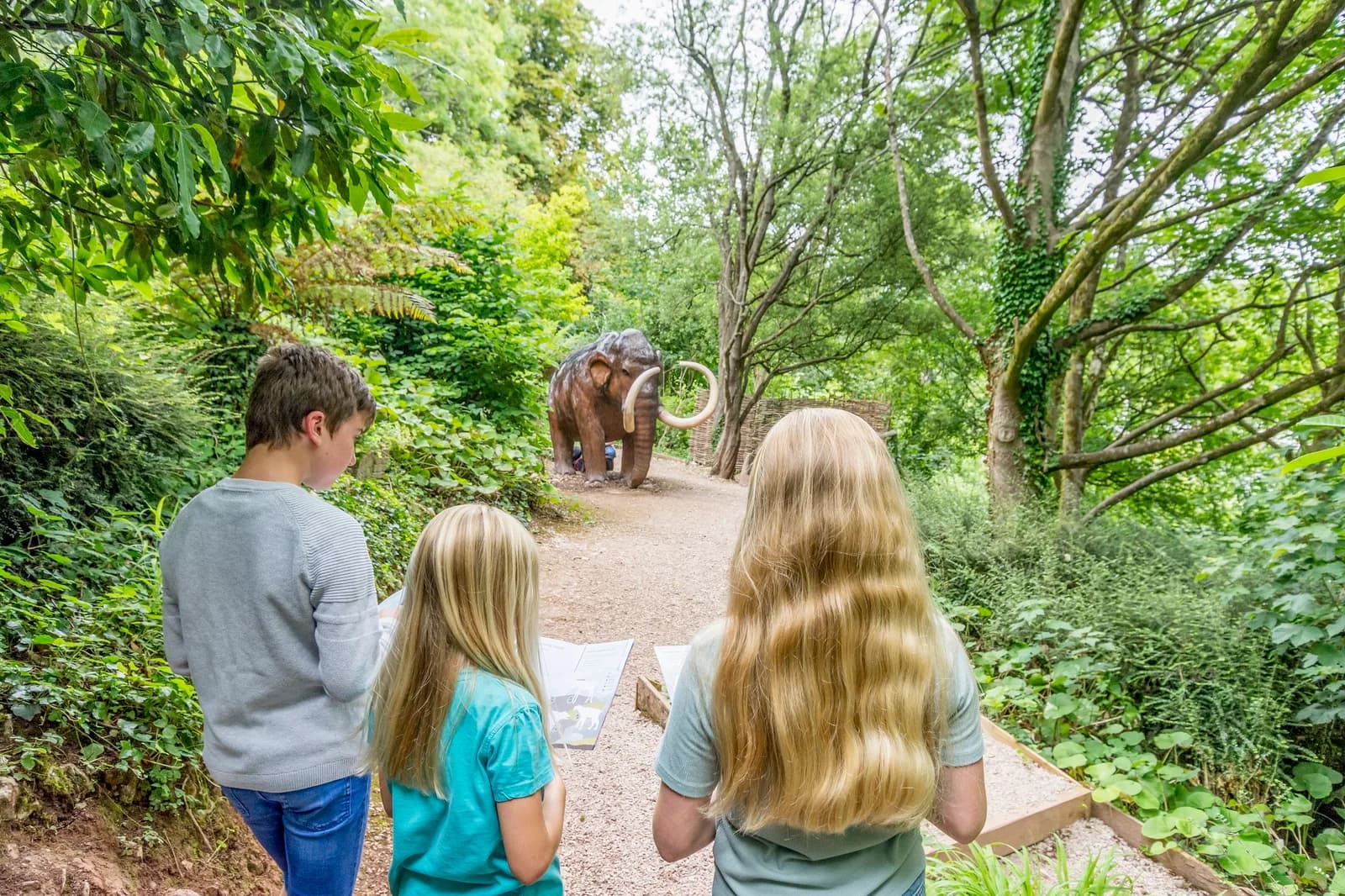 Family on the Woodland Trail towards the woolly mammoth statue at Kents Cavern, Torquay