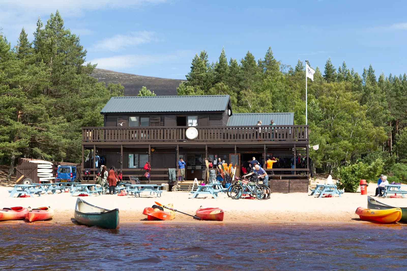 Canoeists and paddleboarders out on Loch Morlich with Cairngorm mountains behind