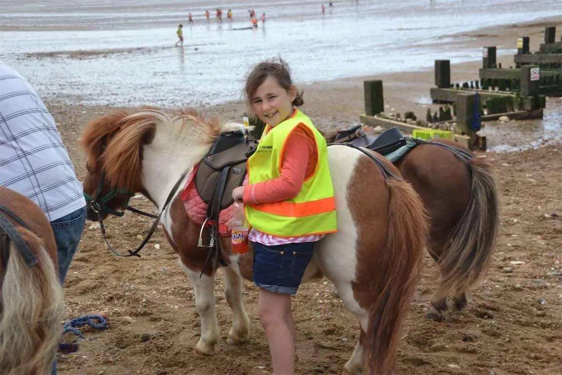 Child with a horse on a beach trip organised by Cambridge Kids Club